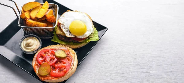 Breakfast. French fries and burger with meat and egg. On a wooden background. Top view. Free space.