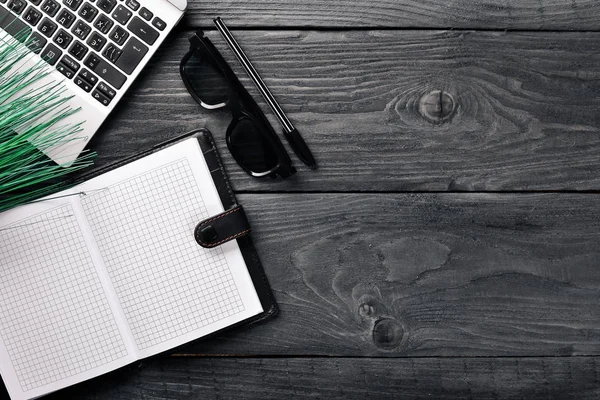 Arbete kontorslokaler, anteckningsboken, laptop och glasögon. På en yta av trä. Ovanifrån. Fritt utrymme för din text. — Stockfoto