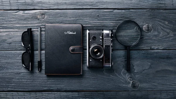 Office work space with camera, notebook, eyepieces, and pen. On a wooden surface. Top view. Free space for your text. — Stock Photo, Image