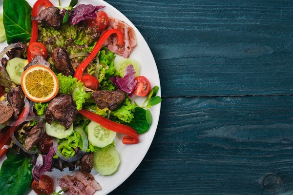 Domuz eti ve tavuk karaciğer salata. Bir ahşap yüzeye. Üstten Görünüm. Metniniz için boş alan. — Stok fotoğraf