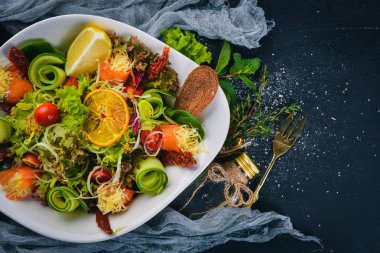 Tuzlanmış somon, peynir ve salata yaprakları salata. Bir ahşap yüzeye. Üstten Görünüm. Metniniz için boş alan.