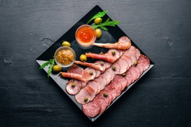 Ketçap ve hardal ile bir tabakta et dilimleri. Sucuk ve pastırma. Ahşap bir arka plan üzerinde. Üstten Görünüm. Boş alan.
