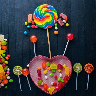 Renkli şeker, tatlılar ve lolipop. Siyah ahşap arka plan üzerinde. Üstten Görünüm. Boş alan.