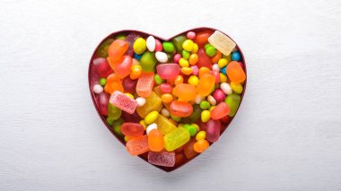 Renkli şeker, tatlılar ve lolipop. Beyaz ahşap zemin üzerinde. Üstten Görünüm. Boş alan.