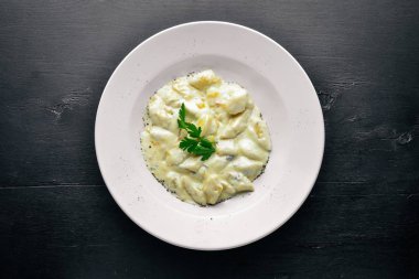 Patates peynir sosu altında gelen hamur tatlısı. Ahşap bir arka plan üzerinde. Üstten Görünüm. Boş alan.