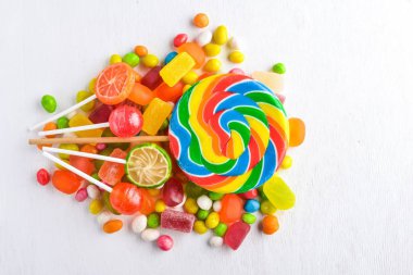 Renkli şeker, tatlılar ve lolipop. Beyaz ahşap zemin üzerinde. Üstten Görünüm. Boş alan.