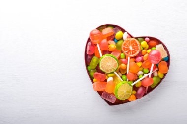 Renkli şeker, tatlılar ve lolipop. Beyaz ahşap zemin üzerinde. Üstten Görünüm. Boş alan.