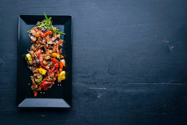 Ψητά λαχανικά με μυρωδικά σε ένα πιάτο. Σε ένα ξύλινο υπόβαθρο. Το Top view. Ελεύθερου χώρου. — Φωτογραφία Αρχείου