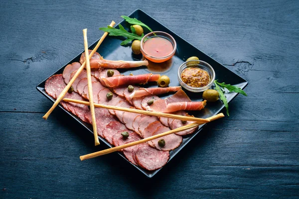 Rebanadas de carne en un plato con ketchup y mostaza. Salchichas y tocino. Sobre un fondo de madera. Vista superior. Espacio libre . — Foto de Stock