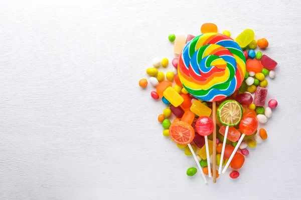 Caramelos de colores, dulces y piruletas. Sobre un fondo de madera blanca. Vista superior. Espacio libre . —  Fotos de Stock