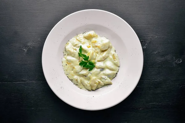 Patates peynir sosu altında gelen hamur tatlısı. Ahşap bir arka plan üzerinde. Üstten Görünüm. Boş alan.