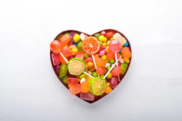 Bunte Bonbons, Süßigkeiten und Lutscher. auf weißem Holzgrund. Ansicht von oben. Freiraum. — Stockfoto