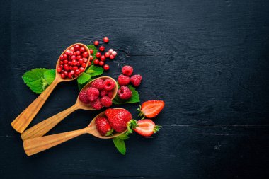 Çilek ürün yelpazesine. Ahududu, böğürtlen, çilek, kızılcık. Ahşap bir arka plan üzerinde. Üstten Görünüm. Metin için boş alan.