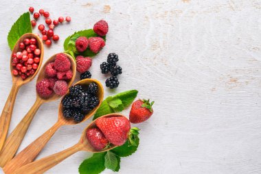 Çilek ürün yelpazesine. Ahududu, böğürtlen, çilek, kızılcık. Ahşap bir arka plan üzerinde. Üstten Görünüm. Metin için boş alan.