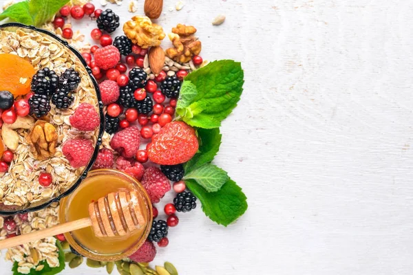 Sağlıklı gıda. Taze yabani çilek, bakır, fındık, yulaf ezmesi, Kuruyemiş ve tohumlar. Ahşap bir arka plan üzerinde. Üstten Görünüm. Metin için boş alan.