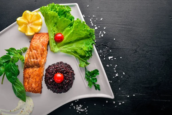 Yabani pirinç pişmiş somon fileto. Ahşap bir arka plan üzerinde. Üstten Görünüm. Metin için boş alan.