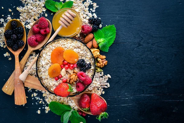 Healthy food. Fresh wild berries, copper, nuts, oatmeal, dried fruits and seeds. On a wooden background. Top view. Free space for text.