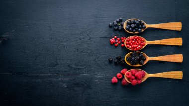 Çilek ürün yelpazesine. Ahududu, böğürtlen, çilek, kızılcık. Ahşap bir arka plan üzerinde. Üstten Görünüm. Metin için boş alan.