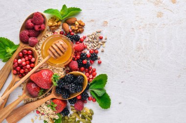 Sağlıklı gıda. Taze yabani çilek, bakır, fındık, yulaf ezmesi, Kuruyemiş ve tohumlar. Ahşap bir arka plan üzerinde. Üstten Görünüm. Metin için boş alan.