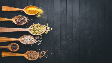 Çeşitli baharatlar kaşık taş masada. Ahşap bir gemide. Üstten Görünüm. Metniniz için boş alan.