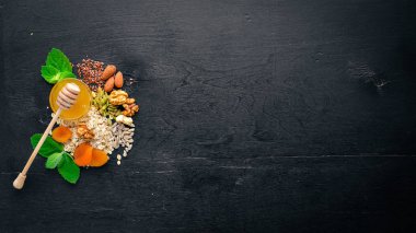 Sağlıklı gıda. Tatlım, fındık, yulaf ezmesi, Kuruyemiş ve kuru kayısı, keten, ayçiçeği çekirdeği. Ahşap bir arka plan üzerinde. Üstten Görünüm. Metin için boş alan.