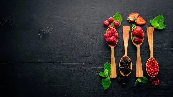 Sortiment av bär. Hallon, björnbär, jordgubbar, tranbär. På en trä bakgrund. Ovanifrån. Ledigt utrymme för text. — Stockfoto