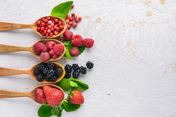 Çilek ürün yelpazesine. Ahududu, böğürtlen, çilek, kızılcık. Ahşap bir arka plan üzerinde. Üstten Görünüm. Metin için boş alan.