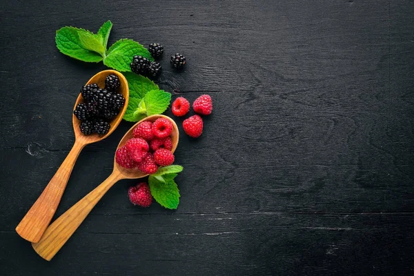 Böğürtlen ve ahududu bir tahta kaşık üzerinde. Ahşap bir arka plan üzerinde. Üstten Görünüm. Metin için boş alan.