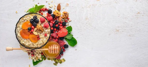 Sağlıklı gıda. Taze yabani çilek, bakır, fındık, yulaf ezmesi, Kuruyemiş ve tohumlar. Ahşap bir arka plan üzerinde. Üstten Görünüm. Metin için boş alan.