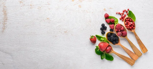 Çilek ürün yelpazesine. Ahududu, böğürtlen, çilek, kızılcık. Ahşap bir arka plan üzerinde. Üstten Görünüm. Metin için boş alan.