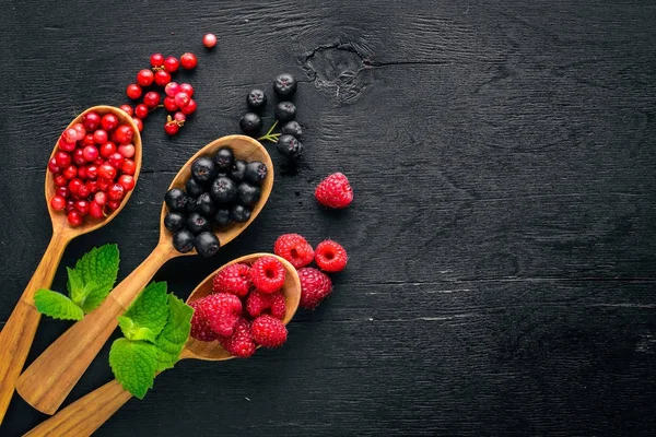 Çilek ürün yelpazesine. Ahududu, böğürtlen, çilek, kızılcık. Ahşap bir arka plan üzerinde. Üstten Görünüm. Metin için boş alan.