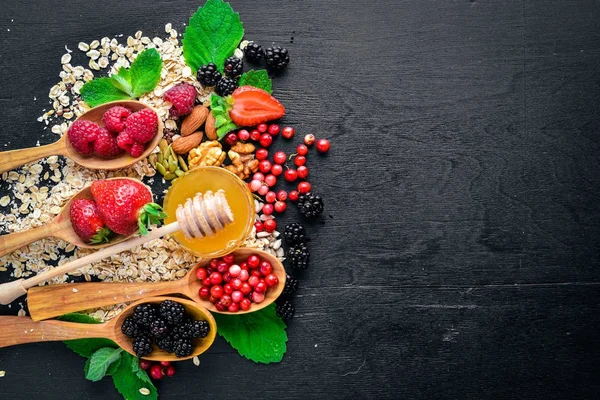 Gesunde Ernährung. frische Waldbeeren, Kupfer, Nüsse, Haferflocken, Trockenfrüchte und Samen. auf einem hölzernen Hintergrund. Ansicht von oben. Freiraum für Text. — Stockfoto