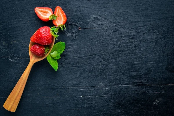 Çilek bir tahta kaşık üzerinde. Ahşap bir arka plan üzerinde. Üstten Görünüm. Metin için boş alan.