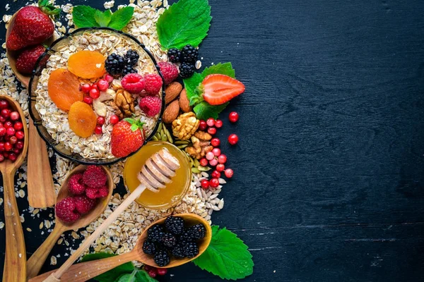 Healthy food. Fresh wild berries, copper, nuts, oatmeal, dried fruits and seeds. On a wooden background. Top view. Free space for text. — Stock Photo, Image