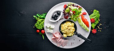 İngiliz kahvaltısı. Yumurta, zeytin, taze sebze, fındık, Kuru Meyve ve bal. Üstten Görünüm. Metin için özgür yer. Ahşap bir arka plan üzerinde.