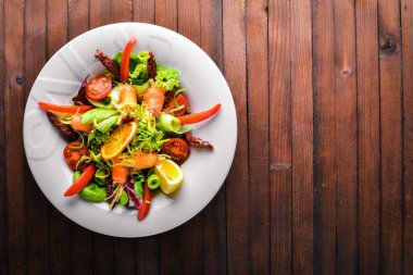 Salata somon ve taze sebze ve otlar. İtalyan mutfağı. Üstten Görünüm. Ahşap arka plan üzerinde.