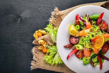 Salata somon ve taze sebze ve otlar. İtalyan mutfağı. Üstten Görünüm. Ahşap arka plan üzerinde.