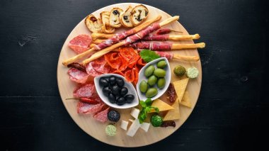 Soğuk aperatifler. Doğranmış sosis, pastırma, zeytin, zeytin. Üstten Görünüm. Ahşap arka plan. Metin için boş alan.