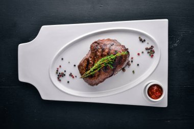 Dana biftek bir plaka üzerinde. Üstten Görünüm. Metin için özgür yer. Ahşap bir arka plan üzerinde.