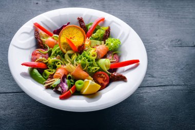 Salata somon ve taze sebze ve otlar. İtalyan mutfağı. Üstten Görünüm. Ahşap arka plan üzerinde.