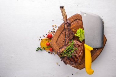 Steak on the bone. Top view. Free space for text. On a wooden background. clipart