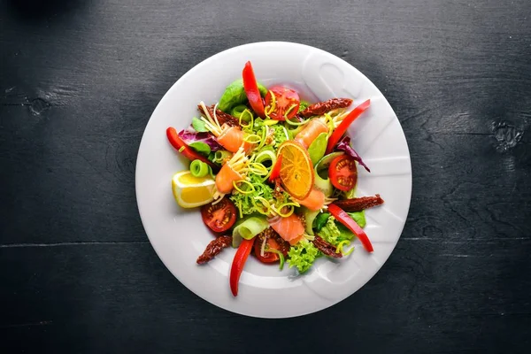 Салат с лососем и свежими овощами и травами. Итальянская кухня. Вид сверху. На деревянном фоне . — стоковое фото