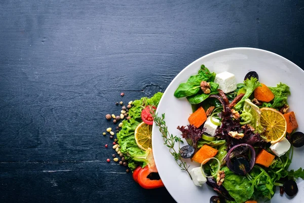 Pumpkin and fresh vegetables salad. Italian cuisine. Top view. Free space for text. On a wooden background. — Stock Photo, Image