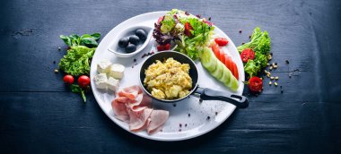 İngiliz kahvaltısı. Yumurta, zeytin, taze sebze, fındık, Kuru Meyve ve bal. Üstten Görünüm. Metin için özgür yer. Ahşap bir arka plan üzerinde.