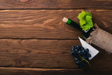 Bir şişe şarap ve üzüm. Ahşap bir arka plan üzerinde. Üstten Görünüm. Metniniz için boş alan.