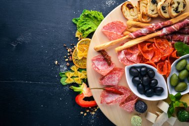 Soğuk aperatifler. Doğranmış sosis, pastırma, zeytin, zeytin. Üstten Görünüm. Ahşap arka plan. Metin için boş alan.
