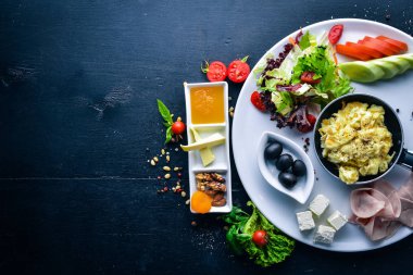 İngiliz kahvaltısı. Yumurta, zeytin, taze sebze, fındık, Kuru Meyve ve bal. Üstten Görünüm. Metin için özgür yer. Ahşap bir arka plan üzerinde.