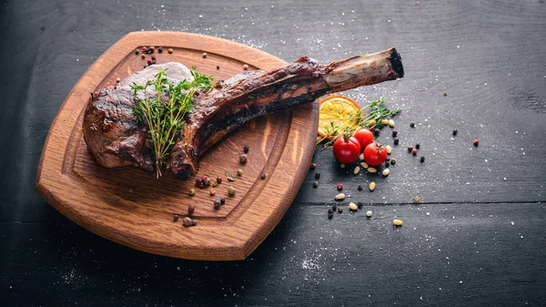 Steak on the bone. Top view. Free space for text. On a wooden background. — Stock Photo, Image