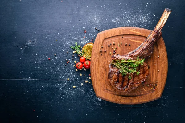 Steak on the bone. Top view. Free space for text. On a wooden background.