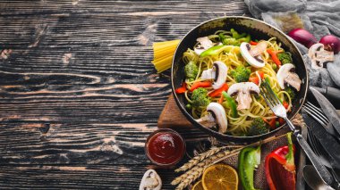 Bir tavada sebzeli erişte. Asya Mutfağı makarna. Üstten Görünüm. Boş alan. Ahşap bir arka plan üzerinde.;